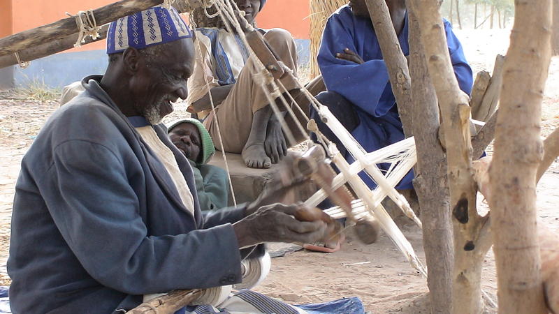 Visit of the village of Bazoulé. An old man weaves